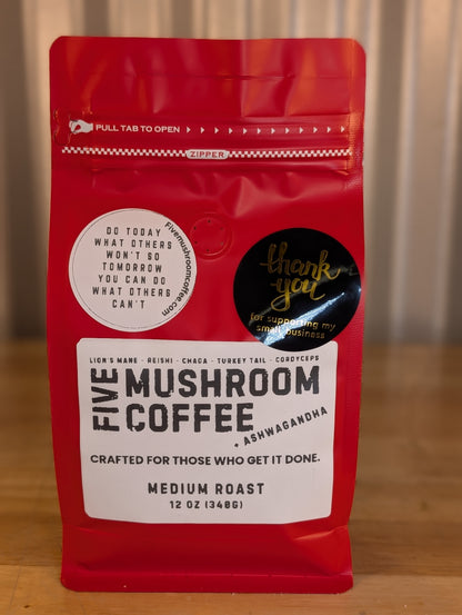 Red coffee bag labeled 'Five Mushroom Coffee' on a wooden surface with a blurred background